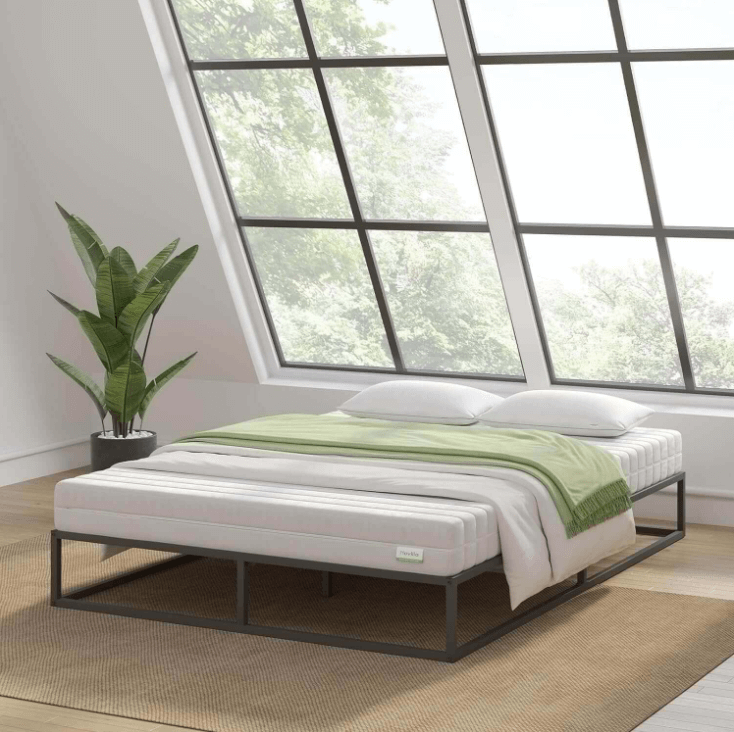 Black metal platform bed frame with pull-out trundle, white bedding, and green throw in a bright modern bedroom