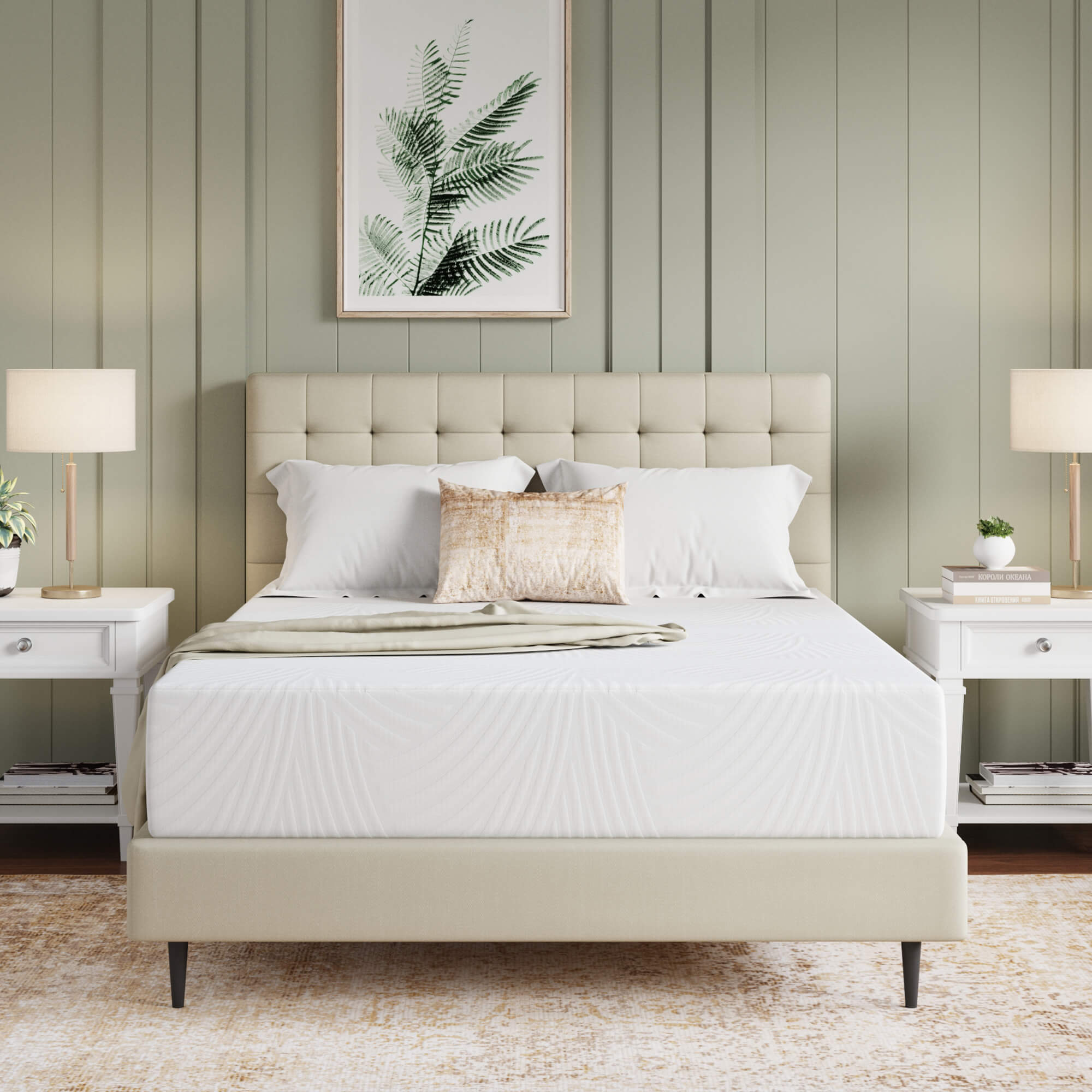 A cream tufted platform bed in a bedroom with a sage green accent wall, flanked by two white nightstands with lamps