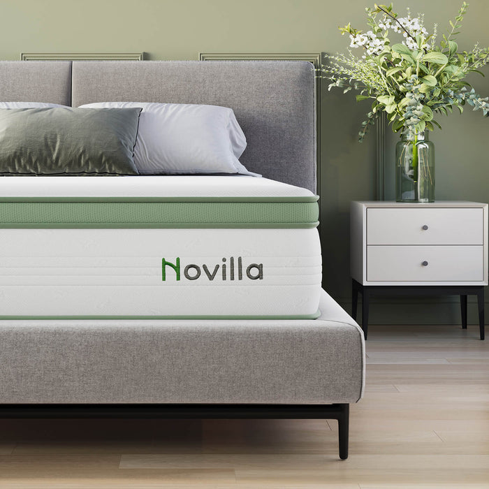 Grove Hybrid Mattress with green border and Novilla logo on a bed with grey headboard and nightstand.
