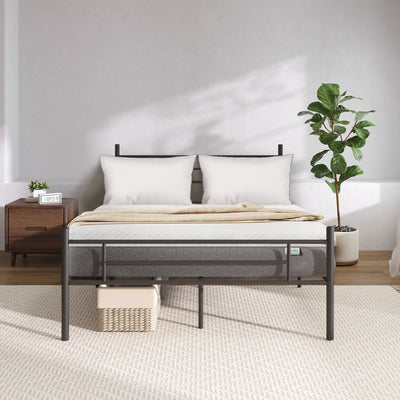 Bliss Silent Support mattress with white pillows and beige throw on black metal bed frame, in a modern bedroom setting.