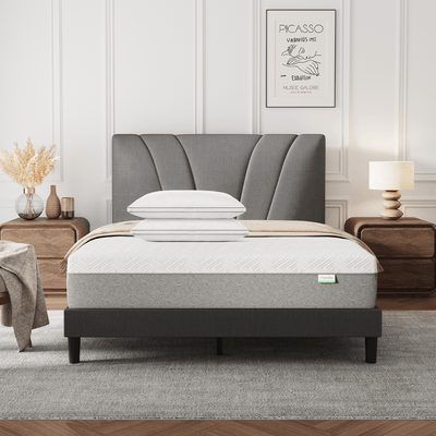 Bliss Adjustable Sleep Bundle: Mattress & pillows on a gray upholstered bed in a modern bedroom setting.