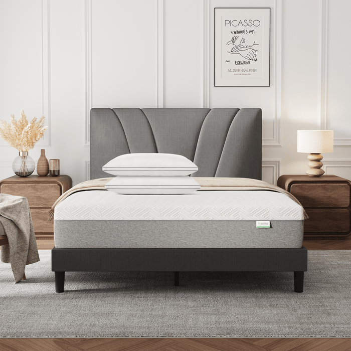 Bliss Adjustable Sleep Bundle: Mattress & pillows on a gray upholstered bed in a modern bedroom setting.