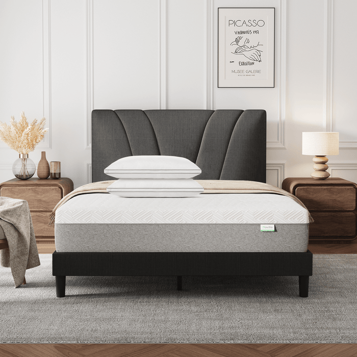 Bliss adjustable sleep bundle with mattress, pillows, and curved gray headboard on a black bed frame in a modern bedroom.